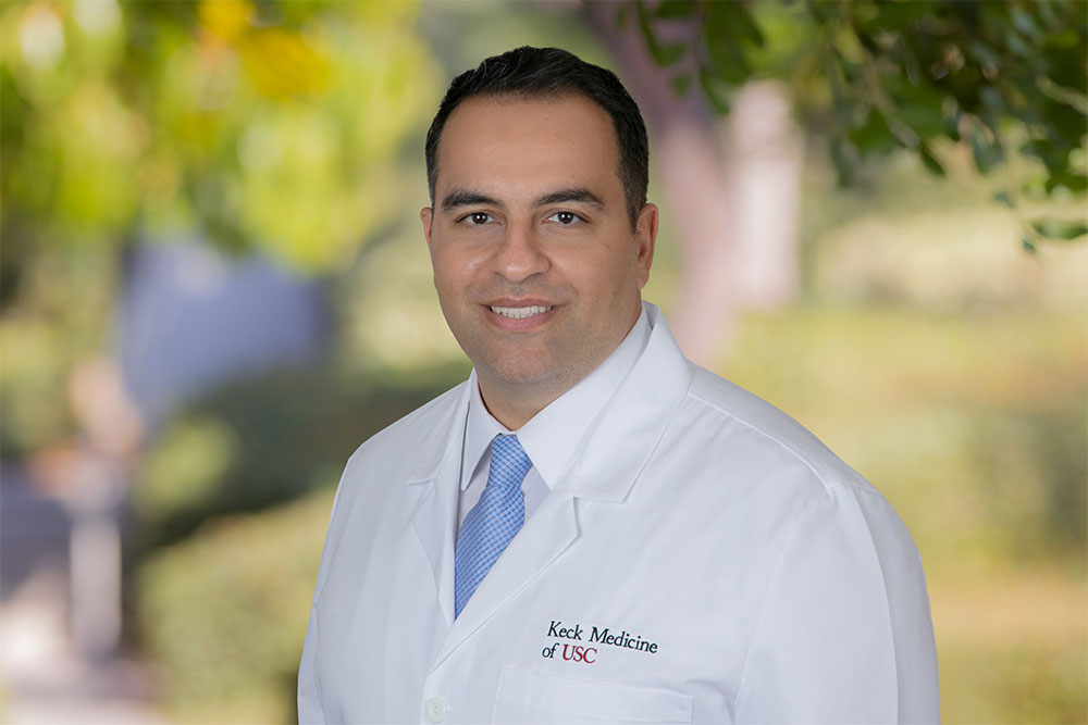 Dr. Amir Lebastchi smiles while wearing a white medical jacket.